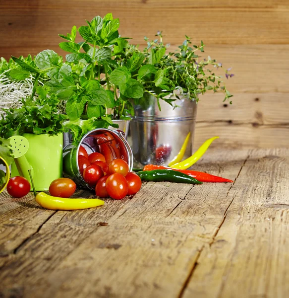 Tomatoes, chives and chili peppers on a wooden table top — Stock Photo, Image