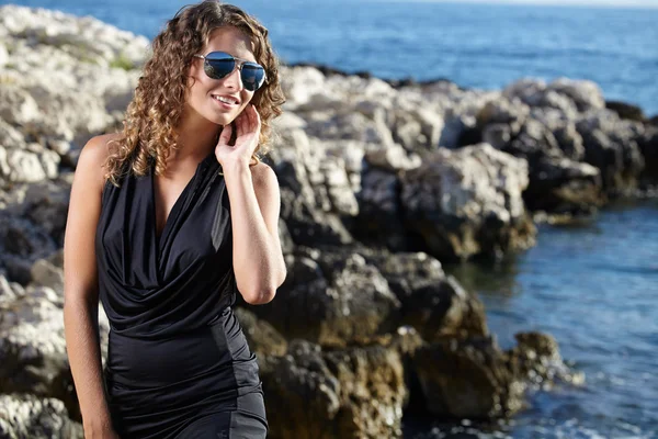 Mulher de vestido preto na costa oceânica — Fotografia de Stock