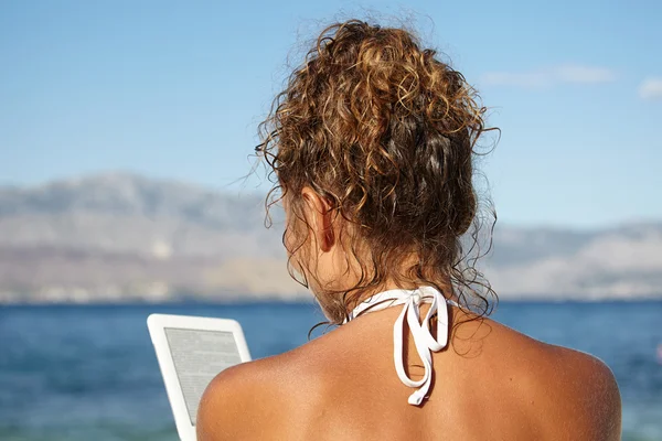 Mujer leyendo ebook en la playa — Foto de Stock