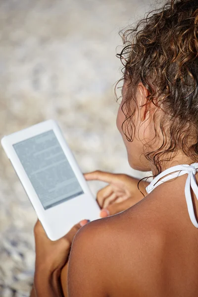 Vrouw leest ebook op het strand — Stockfoto