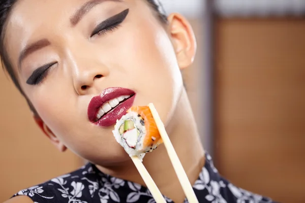 Mujer comiendo sushi con palillos —  Fotos de Stock