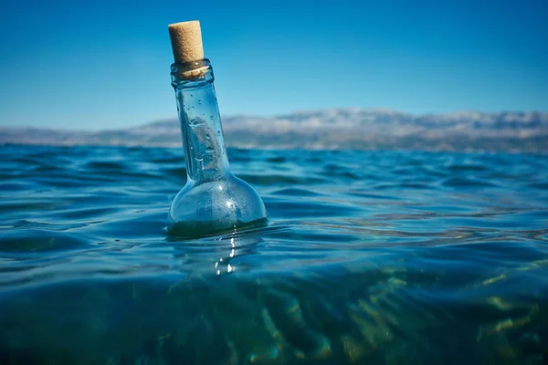 Flaska med ett meddelande i vatten — Stockfoto