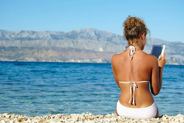 Meisje leest aansteekt op strand — Stockfoto