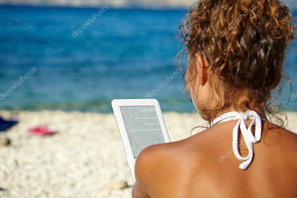 Girl reads kindle on beach — Stock Photo © zoomteam 50037197