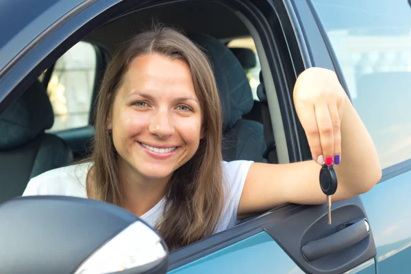 Jonge dame zittend in een auto en sleutel weergegeven: — Stockfoto