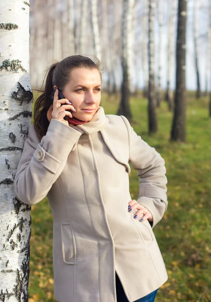 Portret van een meisje onder de berk met telefoon — Stockfoto