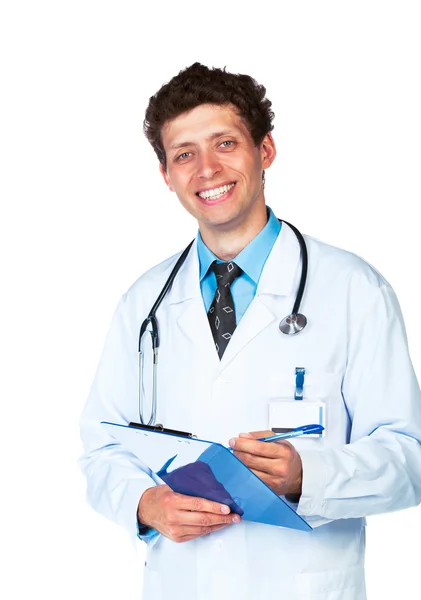 Joven médico sonriente escribiendo en la historia clínica de un paciente en whi —  Fotos de Stock