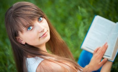 Yeşil çimenlerin üzerinde park kitap ile güzel kız