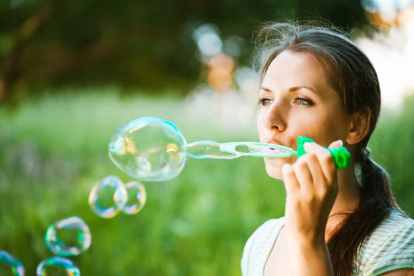 Chica soplando burbujas de jabón en el parque —  Fotos de Stock