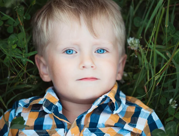 Un niño lindo yaciendo en un campo de verde —  Fotos de Stock