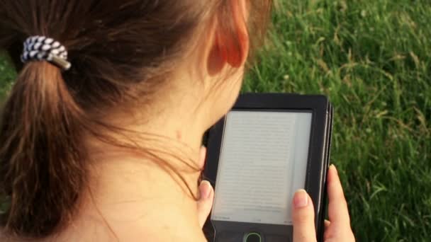 Chica leyendo un libro electrónico en la naturaleza — Vídeos de Stock