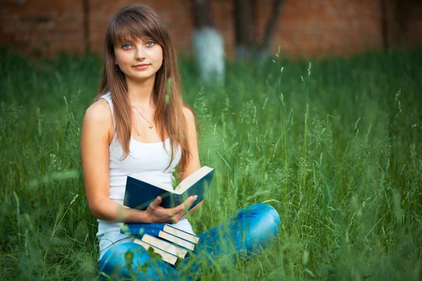 Vacker flicka med bok i parken på grönt gräs — Stockfoto