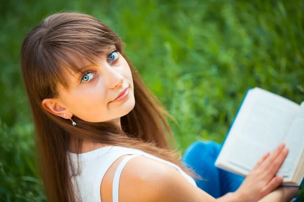 Belle fille avec livre dans le parc sur l'herbe verte — Photo