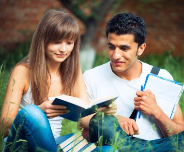 iki öğrenci Park açık havada kitap çim üzerinde okumak