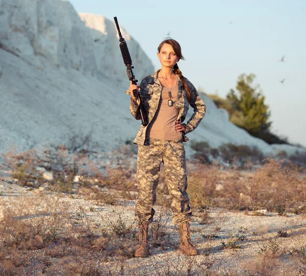 Jovem soldado vestido com uma camuflagem com uma arma no l — Fotografia de Stock