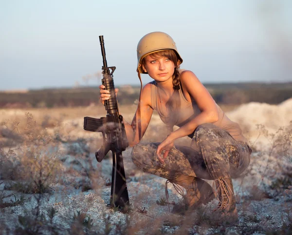 Young female soldier dressed in a camouflage with a gun in the o — Stock Photo, Image