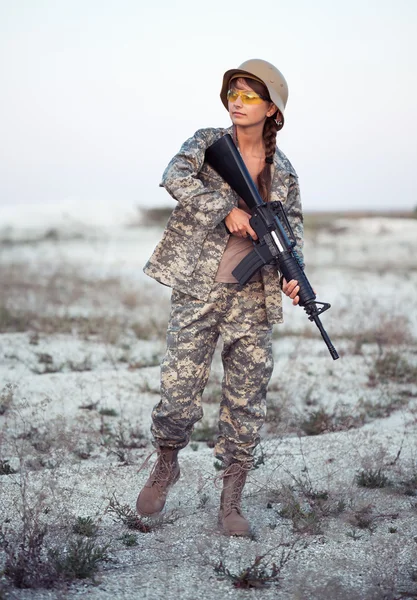 Kvinnlig soldat klädd i ett kamouflage med en pistol i utomhus — Stockfoto