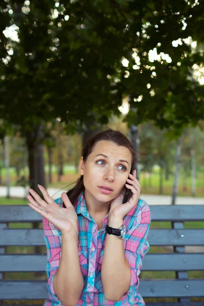 Portrait of a woman in a park on a bench talking on the phone — Stock Photo, Image