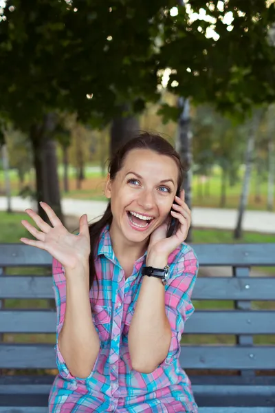 A portrait of a smiling beautiful woman in the park talking on t — Stock Photo, Image