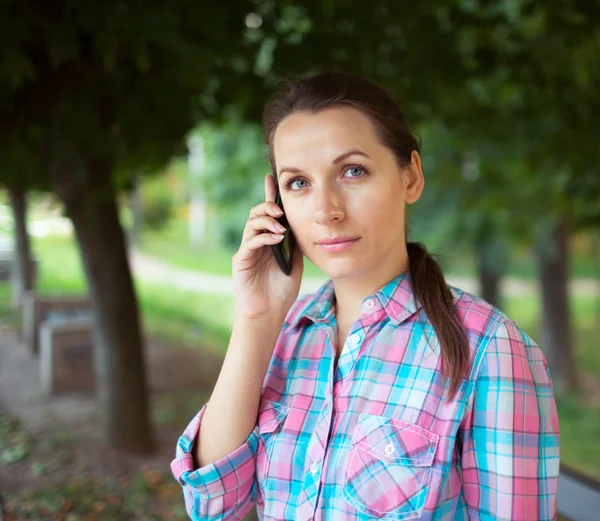 Portrait of a woman in a park talking on the phone — Stock Photo, Image