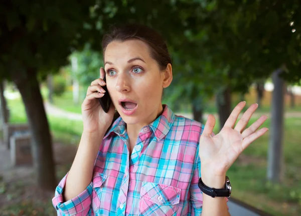 A portrait of a smiling beautiful woman in the park talking on t — Stock Photo, Image