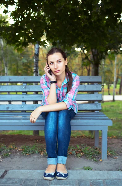 Portret młodej kobiety w parku rozmawia przez telefon — Zdjęcie stockowe