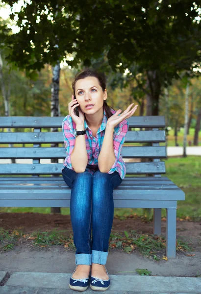 Portrait d'une jeune femme dans un parc parlant au téléphone — Photo
