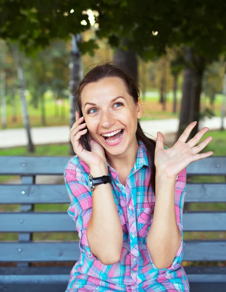 Retrato de uma jovem mulher em um parque falando ao telefone — Fotografia de Stock