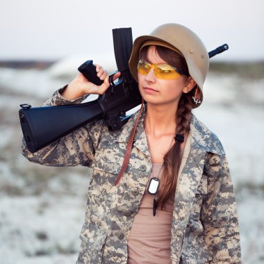 o silahlı bir kamuflaj giyinmiş genç kadın asker