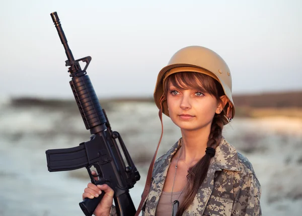 Jonge vrouwelijke soldaat gekleed in een camouflage met een pistool in het o — Stockfoto