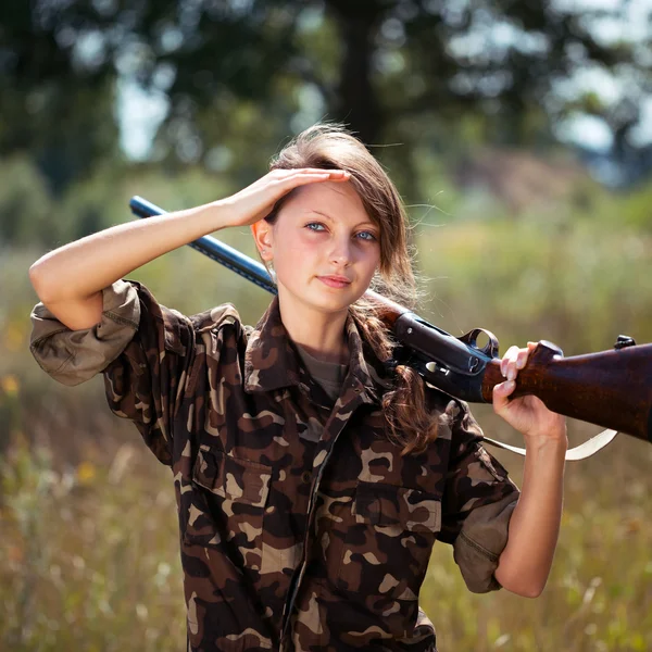 Chica joven con una escopeta mira a la distancia en un exterior — Foto de Stock