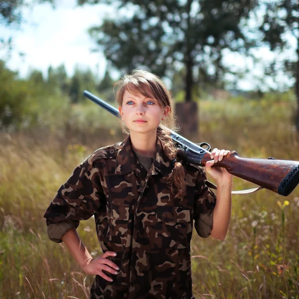 Ung flicka med ett hagelgevär ser in avståndet i en utomhus — Stockfoto