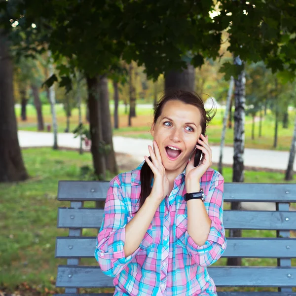 Un retrato de una mujer sonriente en un parque en un banco hablando en th — Foto de Stock