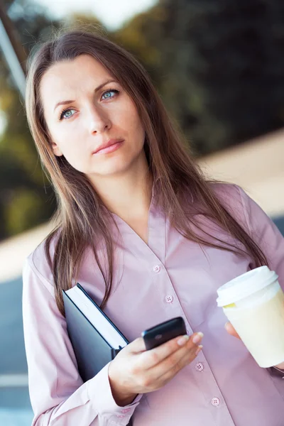 Businesswoman with cellphone and organizer while standing agains — Stock Photo, Image