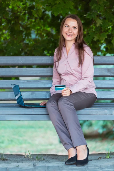 Femme d'affaires avec ordinateur portable et carte de crédit sur le banc — Photo