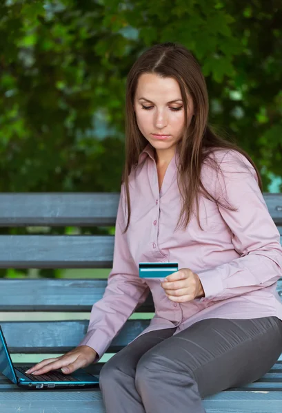 Businesswoman with computer laptop and credit card in the park — Stock Photo, Image