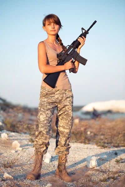 Joven soldado vestida con un camuflaje con un arma en la l —  Fotos de Stock