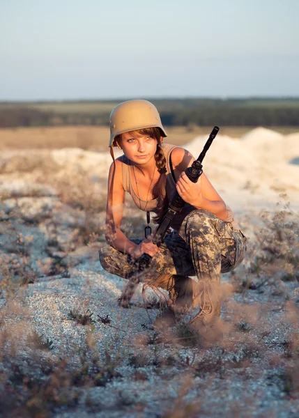 Jovem soldado vestido com uma camuflagem com uma arma no o — Fotografia de Stock
