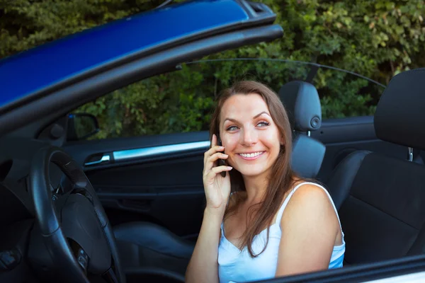 カブリオレの車での携帯電話で話している女性の笑みを浮かべてください。 — ストック写真