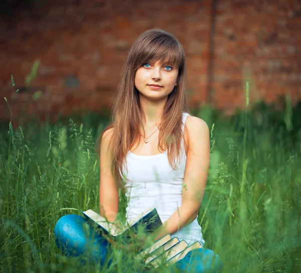 Giovane ragazza con libro nel parco su erba verde — Foto Stock