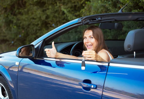 Lachende Kaukasische vrouw sleutel in een cabriolet tonen — Stockfoto