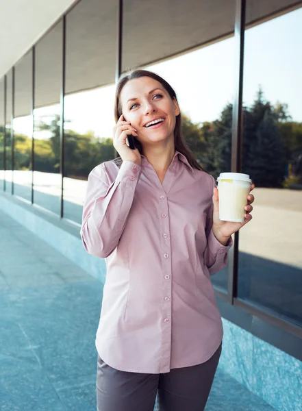 Jonge zakenvrouw met mobiel en koffie terwijl staande aga — Stockfoto