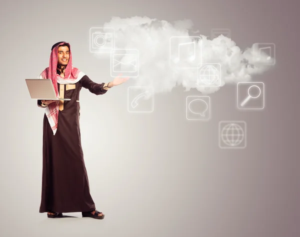 Young smiling arab with laptop shows virtual icons of the cloud — Stock Photo, Image