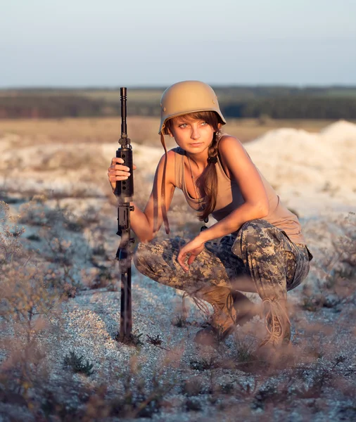 Jonge vrouwelijke soldaat gekleed in een camouflage met een pistool in het o — Stockfoto