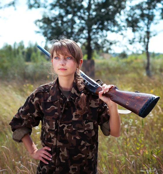 Giovane bella ragazza con un fucile guarda in lontananza — Foto Stock