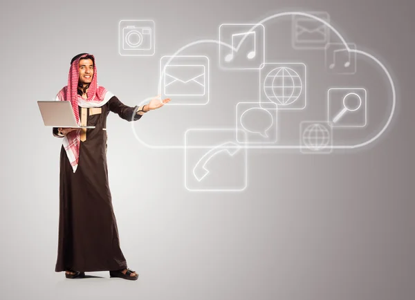 Young smiling arab with laptop shows virtual icons of the cloud — Stock Photo, Image