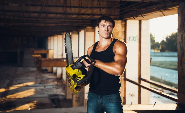 Muscular man with a chainsaw — Stock Photo, Image