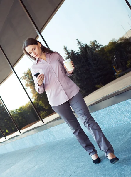 Jeune femme d'affaires avec téléphone portable et tasse de café en plein air — Photo