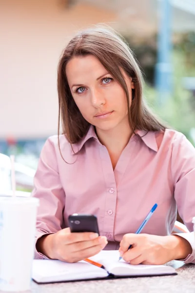 Femme d'affaires assise dans un café et écrivant dans un bloc-notes — Photo