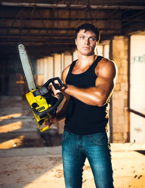 Muscular man with a chainsaw — Stock Photo, Image